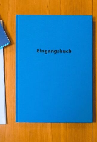 Blaues Buch mit Titel Eingangsbuch auf der Fronstseite.