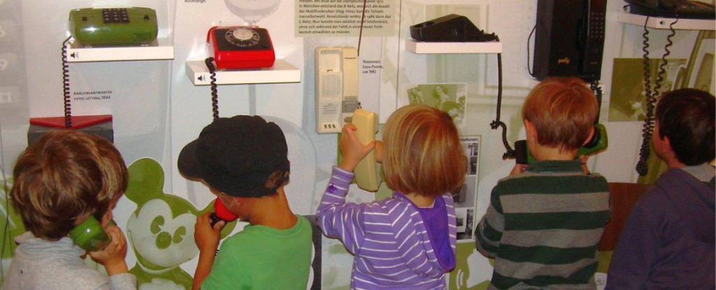 Kinder nehmen Telefone in die Hand und halten sich den Hörer an den Kopf.