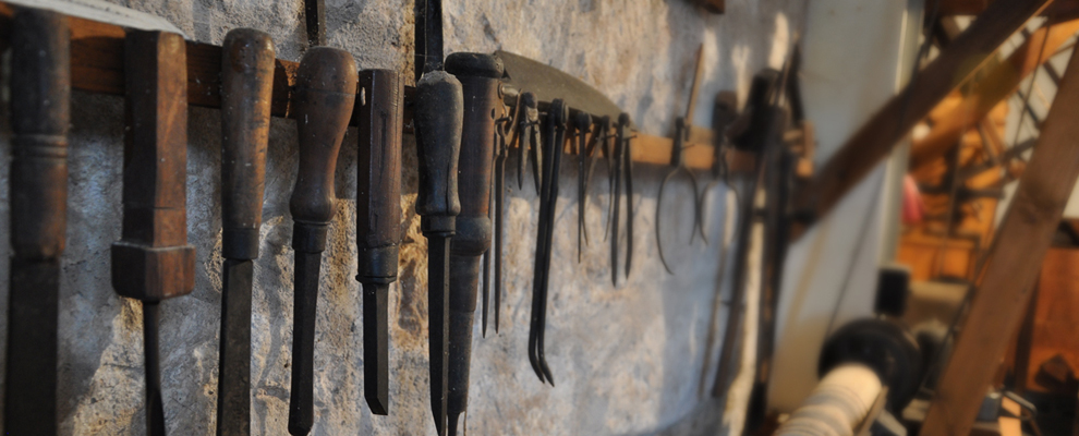 Alte Werkzeuge hängen an einer Wand. Die Werkzeuge werden in einem Museum gezeigt.