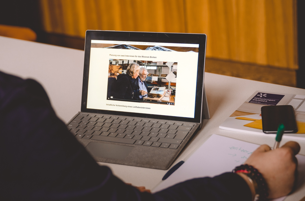 Eine Person sitzt an einem Laptop und hat die Website der Selbstlernkurse des Museumsverbandes Hessen geöffnet.
