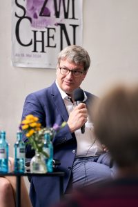 Eckart Köhne mit Mikrofon in der Hand bei der Podiumsdiskussion.
