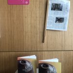 Blick auf die Pop-Up-Ausstellung, die den Verbandstag 2024 begleitete. Detailaufnahme: Im Vordergrund stehen zwei gleiche Bücher auf einer Ausstellungssteele, an der Wand dahinter ist eine Zeitungsklammer angebracht, in der Sieten aus einer Zeitung eingeklemmt sind. Beides sind Beispiele für die wirksame Objektpräsentation.