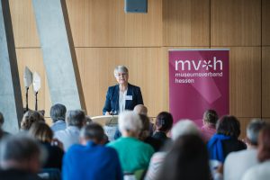 Geschäftsführerin des MVH, Christina Reinsch, steht vor Publikum am Rednerpult.