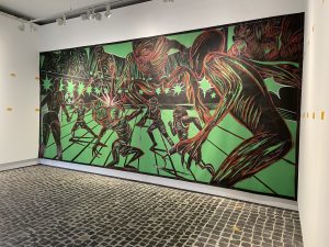 Großformatiges Wandbild, das eine dynamische Fußballszene mit surrealen Elementen zeigt. Die Farben sind stark kontrastreich. Leuchtendes Grün als Hintergrund und schwarzen sowie roten Linien für die Figuren. Neben den Fußballspielern sind bedrohlich wirkende, übernatürliche Wesen mit großen Krallen und verzerrten Gesichtern dargestellt. Die Szene strahlt Spannung und Bewegung aus.