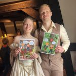 Im Ausstellungsraum stehen in zeittypischer Kleidung die historischen Personen Isabella und Eduard. Sie halten Zettel für die Vermittlung in der Hand.