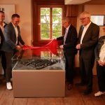Mehrere Personen stehen im Museumsraum um ein Stadtmodell, das von Bürgermeister Mario Schramm und Landrat Carsten Braun enthüllt wird.