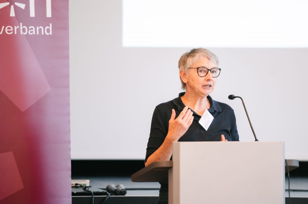 Dr. Martina Lüdicke steht an einem Rednerpult mit Mikrofon und spricht Richtung Publikum. Im Hintergrund ist ein dunkelroter Banner des Museumsverbandes mit Logo und eine Leinwand zu sehen.