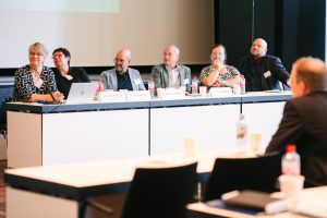 Von links nach rechts sitzen Christina Reinsch (Geschäftsführung MVH), Dr. Birgit Kümmel, Dr. Dirk Pörschmann, Dr. Markus Miller, Dr. Erika Dittrich und Christian Kunz (alle Vorstandsmitglieder) in einer Tischreihe und schauen Richtung Rednerpult.