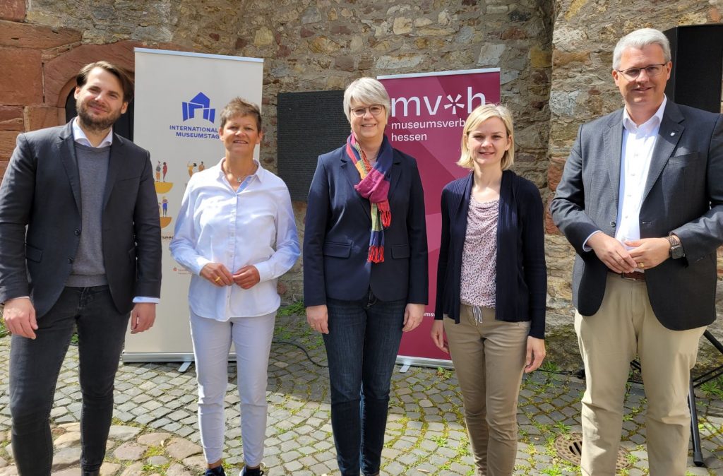 5 Personen stehen nebeneinander und blicken Richtung Kamera. Im Hintergrund sind die Festungsmauer sowie die Banner zum Internationalen Museumstag und des Museumsverbandes Hessen zu shene. Die Personen sind v.l.n.r Nicolas Lange (Museumsleiter), Nicole Schlabach (Sparkassen-Kulturstiftung Hessen-Thüringen), Christina Reinsch (Geschäftsführerin MVH), Bernadette Gorsler (Koordinatorin IMT MVH), Oberbürgermeister Patrick Burghard