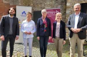 5 Personen stehen nebeneinander und blicken Richtung Kamera. Im Hintergrund sind die Festungsmauer sowie die Banner zum Internationalen Museumstag und des Museumsverbandes Hessen zu shene. Die Personen sind v.l.n.r Nicolas Lange (Museumsleiter), Nicole Schlabach (Sparkassen-Kulturstiftung Hessen-Thüringen), Christina Reinsch (Geschäftsführerin MVH), Bernadette Gorsler (Koordinatorin IMT MVH), Oberbürgermeister Patrick Burghard