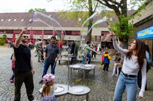 Im Festungshof erzeugen Kinder und Erwachsene große Seifenblasen.