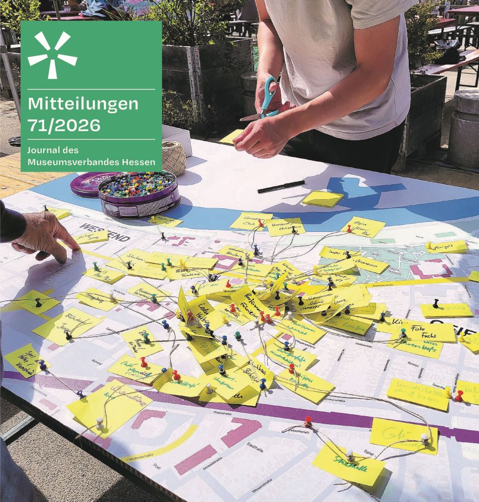 Zwei Menschen stehen an einem Tisch und gestalten gemeinsam eine Stadtkarte mit Notizzetteln, Stecknadeln und Fäden; darüber auf grünem Untergrund der Titel 
