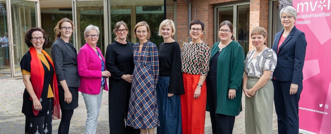 Das Team des Museumsverbandes Hessen steht vor einem Gebäude und lächelt in die Kamera.